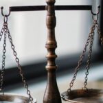 Legal Considerations - Decorative judgement scale and gavel placed on desk in light lawyer office against window